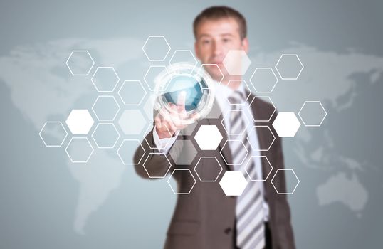 Businessman in suit finger presses virtual button. Transparent hexagons, glow circles and world map as backdrop