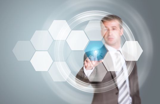 Businessman in suit finger presses virtual button. Transparent hexagons and glow circles as backdrop