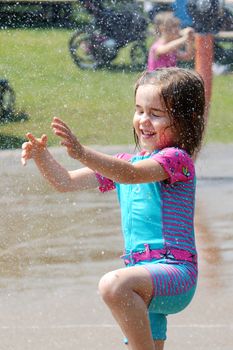 Little girl playing at the water park, focus on the droplets