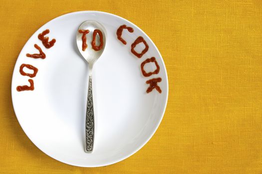 love to cook written by tomato sauce on white plate and silver spoon