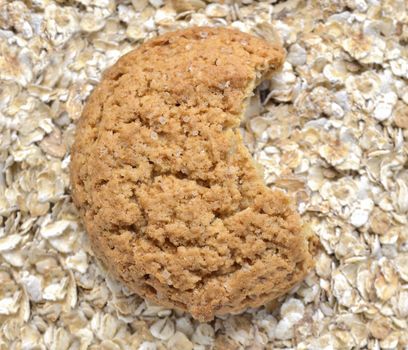 bitten oat cookie over oat flakes background