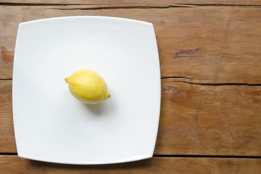 lemon on white ceramic square dish on the vintage wooden table