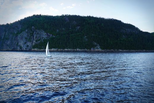 Small sailboat on a fjord, dramatic cold blue and vignetting rendering