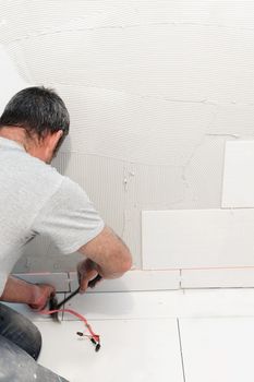 Worker laying down white ceramic or procelain tiles on the wall, reno or construction concept