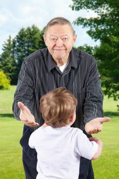 Happy senior man or grand father bending down with open arms to welcome grand kids.