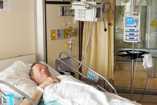 Senior man lying in hospital bed getting oxygen in intensive care unit