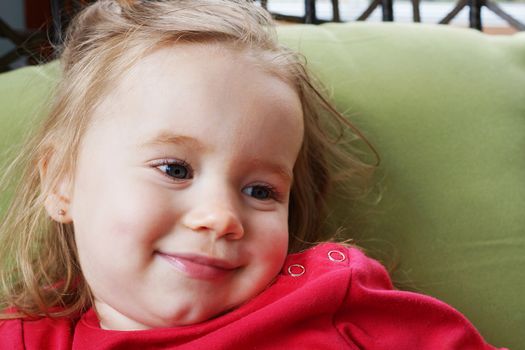 Portrait of a cute blond baby girl smiling, looking away.