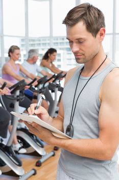 Portrait of a trainer with people working out at spinning class in gym