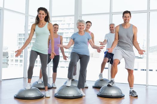 Full length portrait of smiling people doing power fitness exercise at yoga class