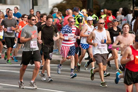 Atlanta, GA, USA - July 4, 2014:  A runner dressed in stars and stripes from head to toe, runs toward the finish line of of the Atlanta Peachtree Road Race on Independence Day.