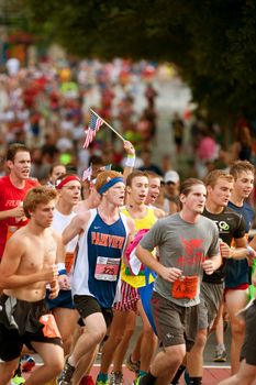 Atlanta, GA, USA - July 4, 2014:  A hand holding a small American flag rises above a throng of runners nearing the finish line of the Peachtree Road Race.