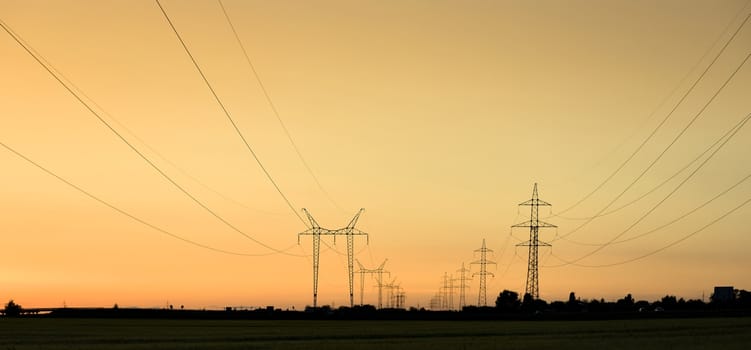 Large transmission towers at sunset with horizon