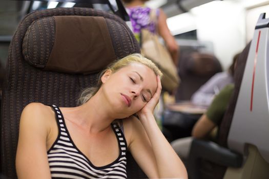 Blonde casual caucasian lady napping while traveling by train.