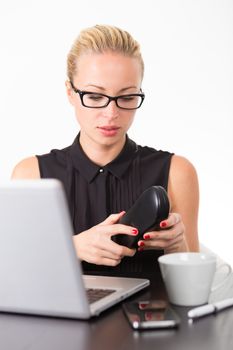 Business woman putting on her black diopter glasses to work on laptop computer in office. 