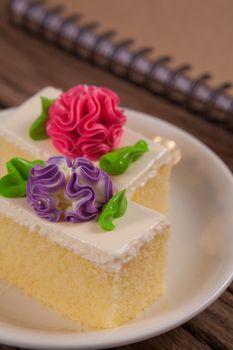 Flower Cake in white dish and notebook on the wood table