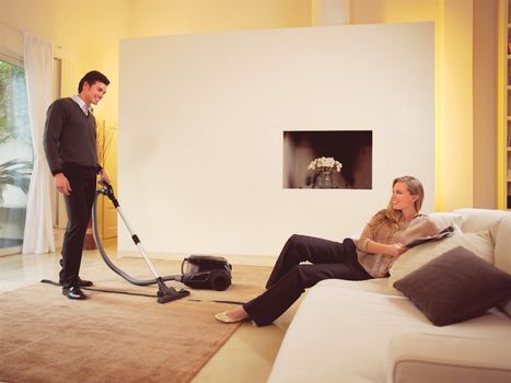 happy man cleaning the carpets in house an woman