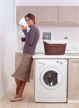 woman enjoys a smell of the washed things in laundry room 