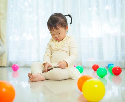 Happy little asian girl using mobile phone in the home