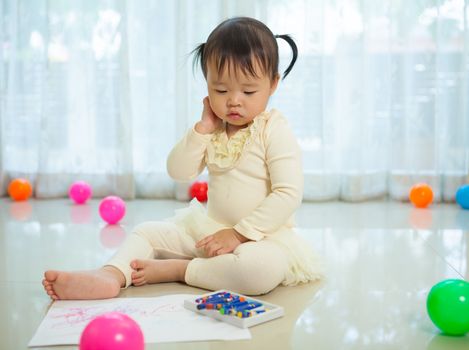 Happy asian baby girl painting with colors in house