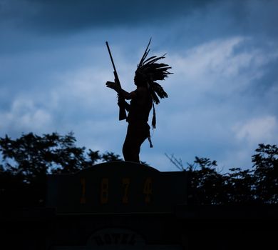 Silhouette of American Indian warrior man with feather headdress and tomahawk