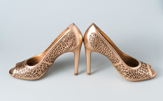 Woman gold shoes on gray background