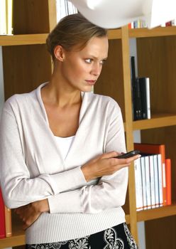 mid adult woman with her mobile phone near shelf