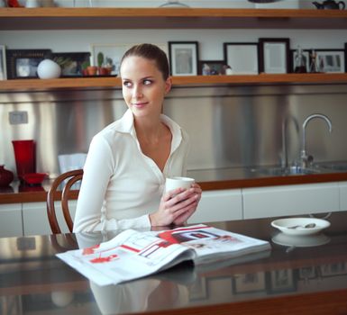 Relaxed woman drinking coffee in kitchen and looking out the window 