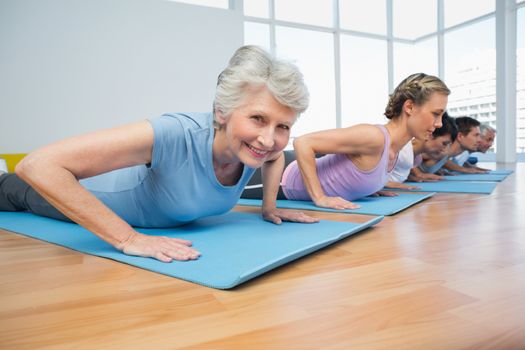 Fitness group doing cobra pose in row at the yoga class