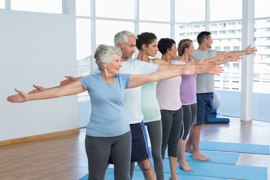 Portrait of fitness class stretching hands in row at yoga class