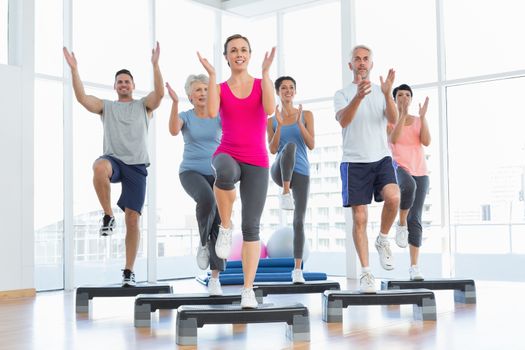 Portrait of smiling people doing power fitness exercise at yoga class in fitness studio