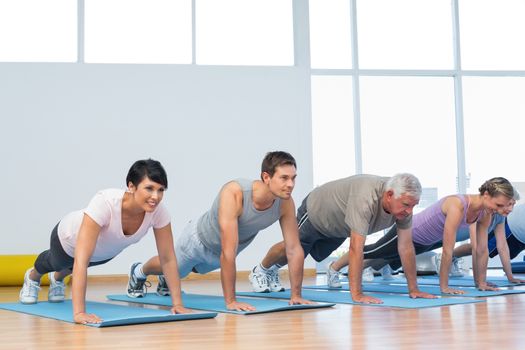 Fitness group doing push ups in row at the yoga class