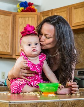 Mother in kitchen kisses her baby