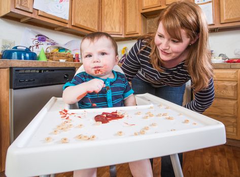 A woman feeds her baby breakfast in the kitchen