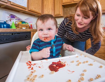 A woman feeds her baby breakfast in the kitchen