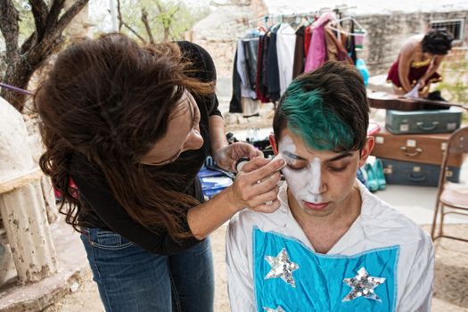 Female makeup artist putting makeup on male clown