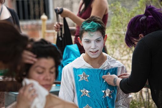 Makeup artist dressing clown with green hair and star shirt