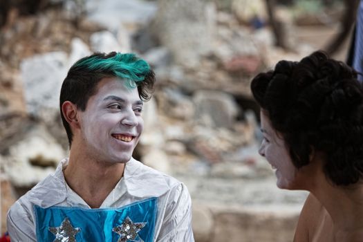 Clown with green hair laughing backstage with partner