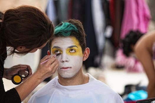 Make up artist painting face of young clown