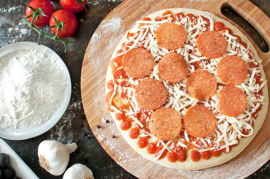 Pepperoni pizza preparation with fresh ingredients on  a kitchen table 