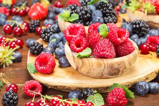 Close up of fresh berry fruits in olive wood bowl