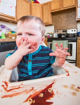 A grumpy child eats breakfast in the kitchen