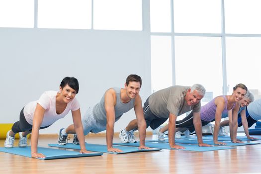 Fitness group doing push ups in row at the yoga class