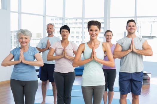 Portrait of sporty people with joined hands at a bright fitness studio