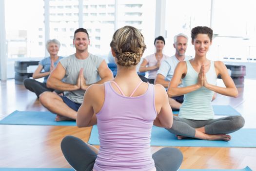 Sporty people with joined hands sitting at fitness studio