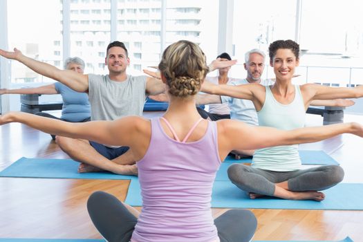 Trainer with sporty people stretching hands at a bright fitness studio