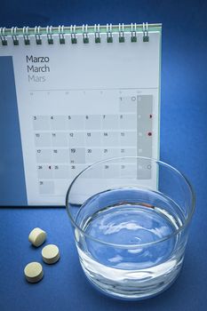 Glass of water and pills isolated on blue