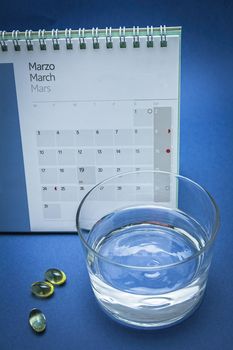 Glass of water and pills isolated on blue