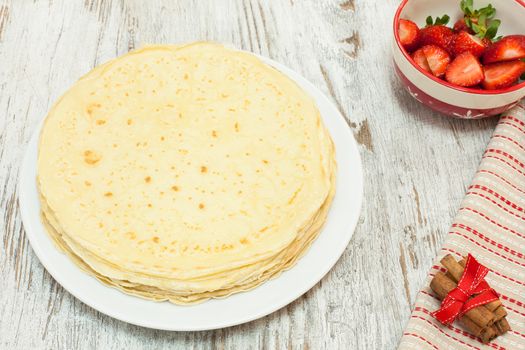 Fresh homemade crepes on plate with ingredients and strawberry, Above view.