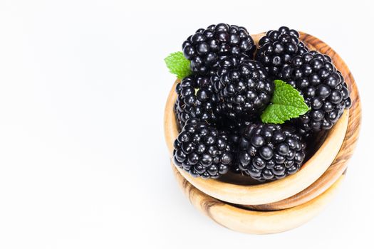 Fresh organic blackberries in olive wood bowl on white background . Copy space composition