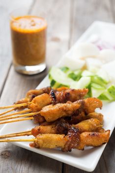 Tasty chicken satay on wooden dining table, one of famous Malaysian local dishes.